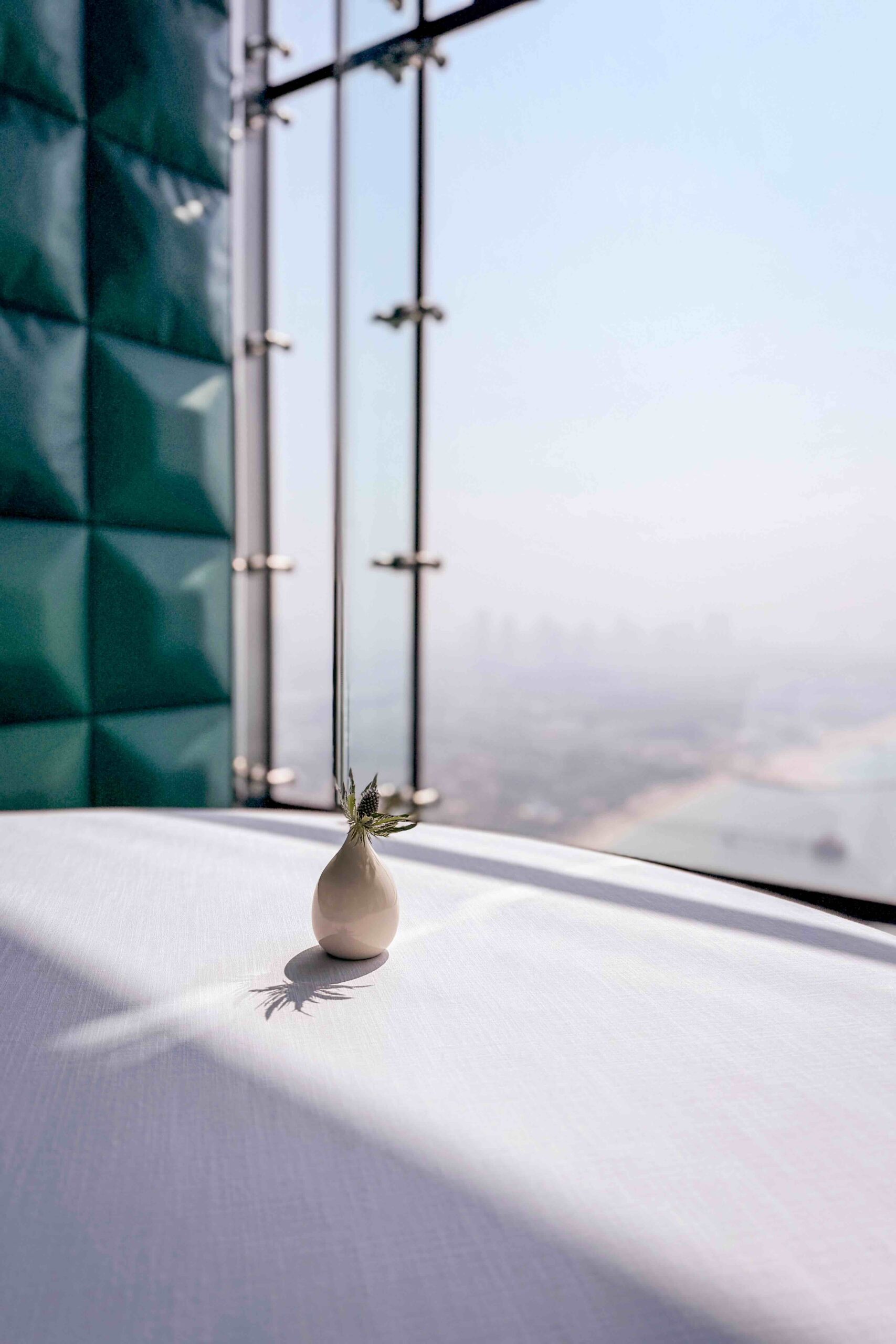 Al Muntaha's view from the Burj Al Arab overlooking the Dubai skyline with a small vase in the foreground.