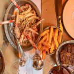 Inside The Devonshire, a pub in central London known for its Guinness and grill cooking. These are langoustines served with duck fat chips and a rib eye steak in the corner. There are glasses of New Zealand Pinor Noir in the lower half of the photo.