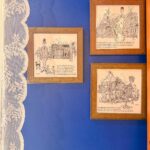 Framed illustrations of Goan characters and street scenes on a blue wall inside Eric’s Restaurant in Karama, Dubai