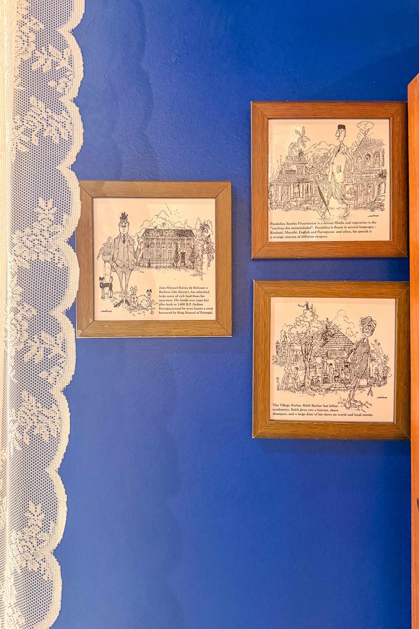 Framed illustrations of Goan characters and street scenes on a blue wall inside Eric’s Restaurant in Karama, Dubai