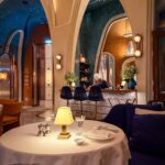 Interior of Rialto showing a white-clothed dining table, high arched openings, blue walls and a chef working behind the counter.