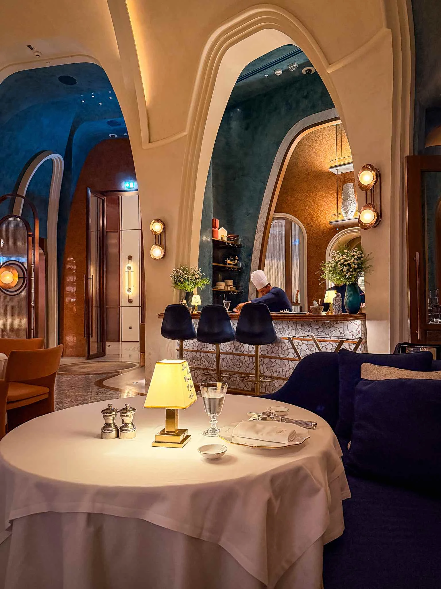 Interior of Rialto showing a white-clothed dining table, high arched openings, blue walls and a chef working behind the counter.