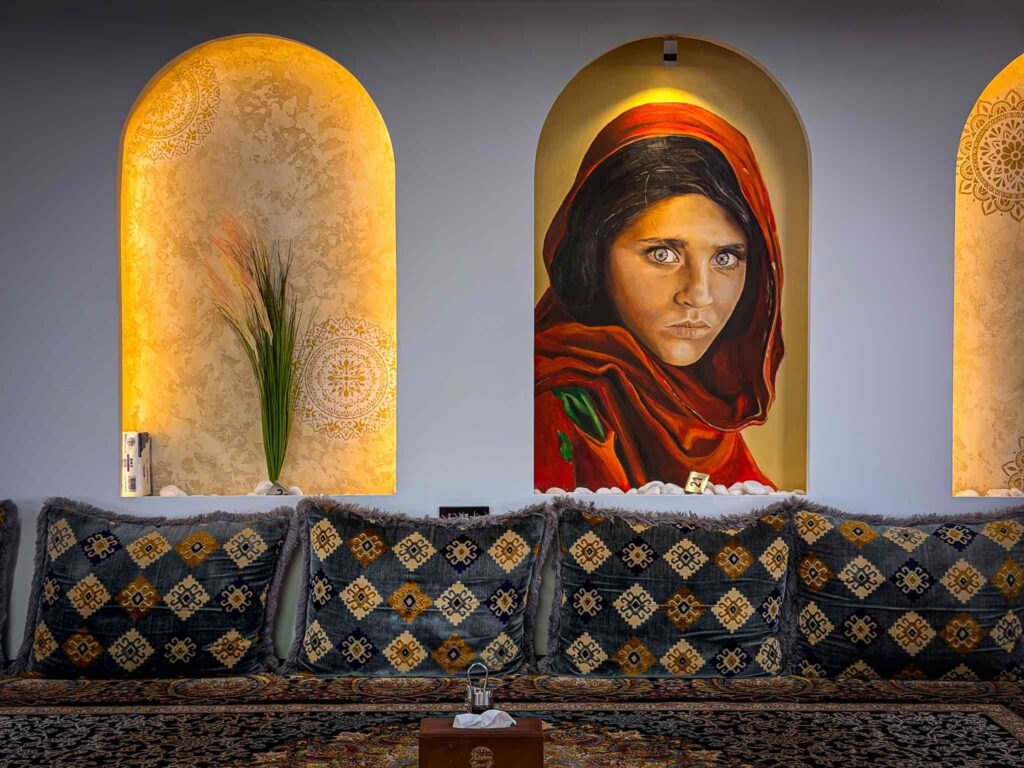 Close view of the hand-painted Afghan Girl mural in a gold-washed arched alcove at Afghan Kabab Village, Deira