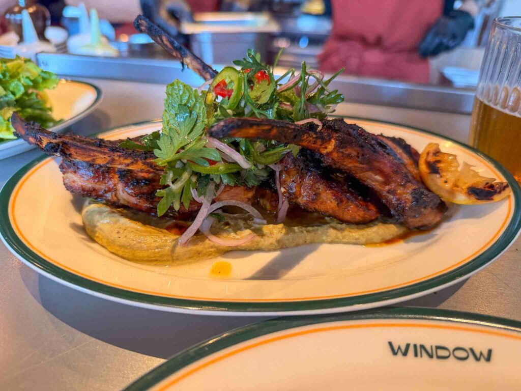 Wood-grilled bone-in [pork/lamb, confirm] chops on aubergine purée [confirm] with herb, chilli and red onion salad and charred lemon at Window, Dubai