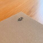 Linen-bound menu cover at Blue restaurant, Abu Dhabi, printed with a small flower motif, on an oak table