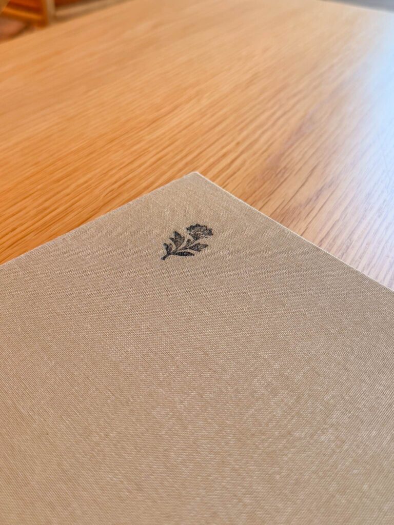 Linen-bound menu cover at Blue restaurant, Abu Dhabi, printed with a small flower motif, on an oak table
