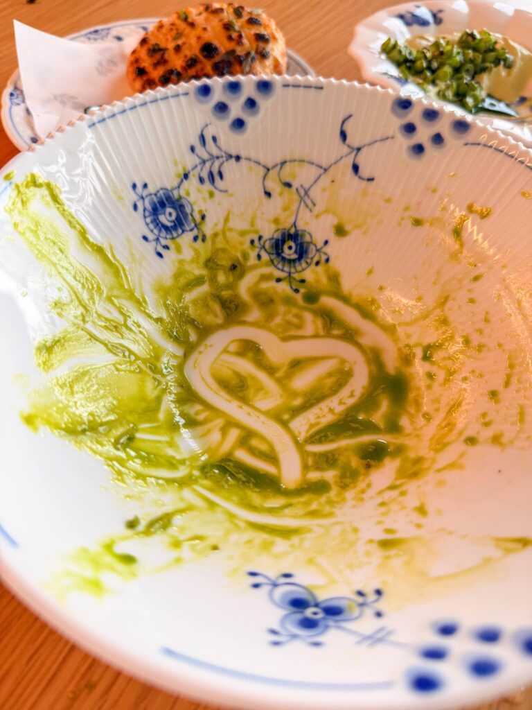 An almost empty Royal Copenhagen bowl streaked with green parsley cream after the salad at Blue, Abu Dhabi