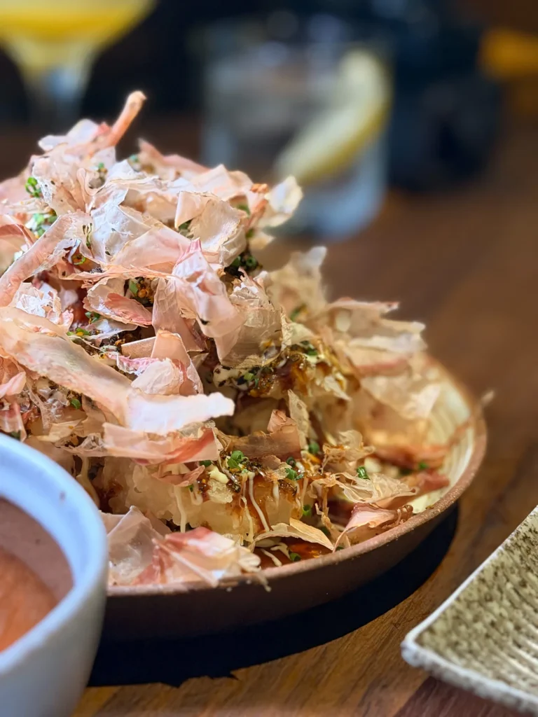 Okonomi tempura onion rings at Noren in JLT, piled under bonito flakes with okonomi sauce, mayonnaise and spring onion, served with a chilli dip