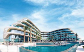 Jebel Ali Lake View hotel from the view of the pool looking back onto the hotel with a bright blue sky.