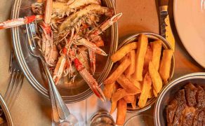 Inside The Devonshire, a pub in central London known for its Guinness and grill cooking. These are langoustines served with duck fat chips and a rib eye steak in the corner. There are glasses of New Zealand Pinor Noir in the lower half of the photo.