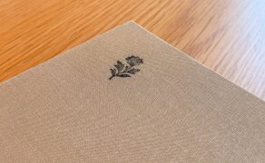 Linen-bound menu cover at Blue restaurant, Abu Dhabi, printed with a small flower motif, on an oak table