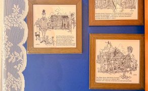 Framed illustrations of Goan characters and street scenes on a blue wall inside Eric’s Restaurant in Karama, Dubai